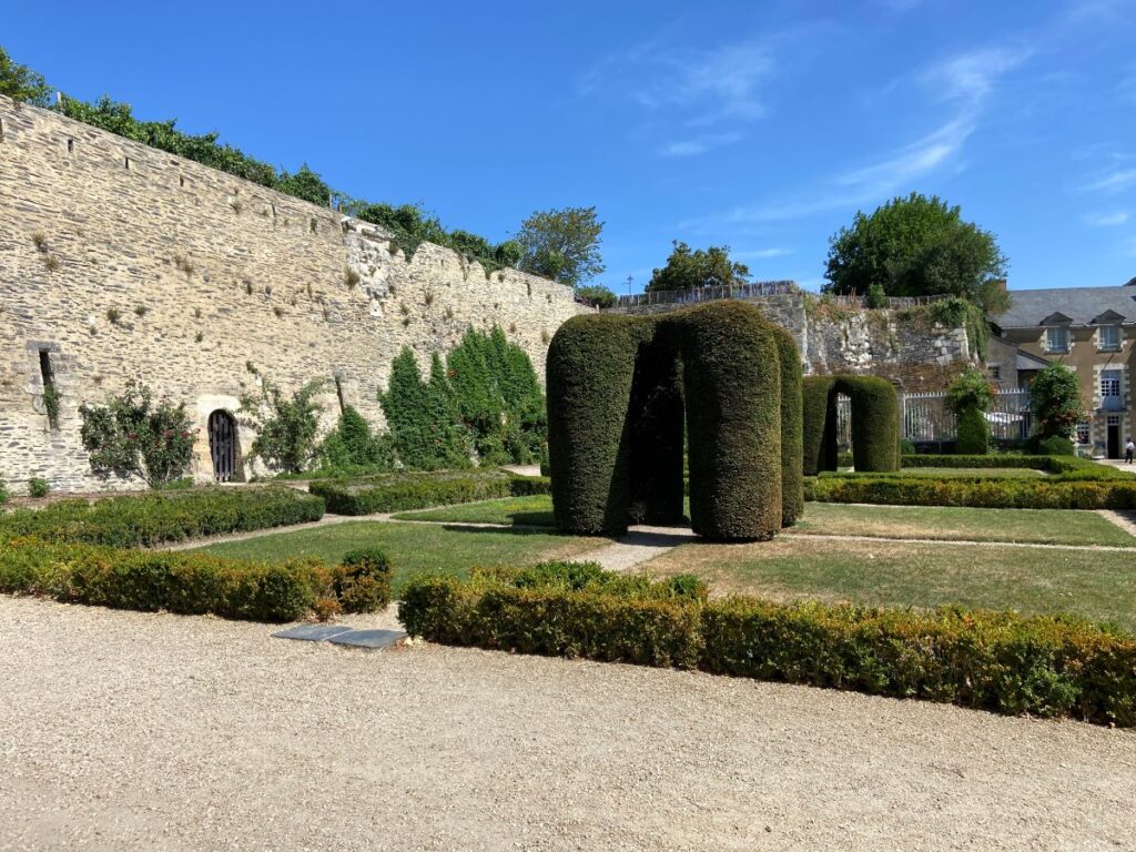 Angers Chateau gardens with wall and huge yew columns in garden at middle
