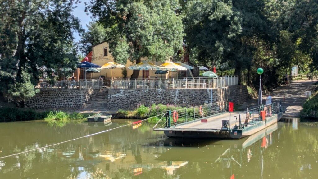 Au Port de l'ile guinguette Angers with small ferry crossing river and restaurant on bank opposite shaded by trees